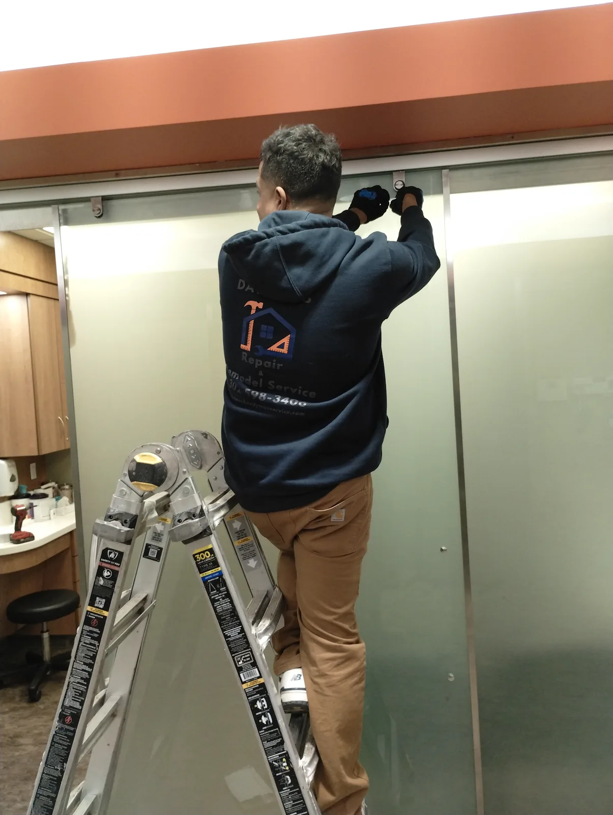 Technician working from a ladder on commercial interior repair